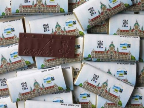 Kleine Schokoladentäfelchen, deren Verpackung mit dem Rathausbild Hannovers und dem Fair-Trade-Siegel versehen ist.