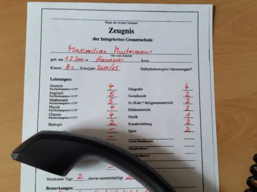 Zeugnis mit schlechten Noten, auf dem ein Telefonh&ouml;rer liegt.