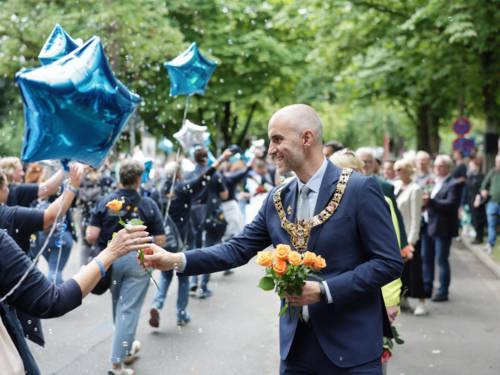 Ein Mann verteilt Blumen an die Menschen beim Festzumzug.