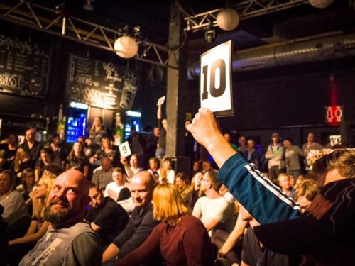 Eine Person im Publikum hält ein Stück Papier mit der Zahl 10 in die Luft