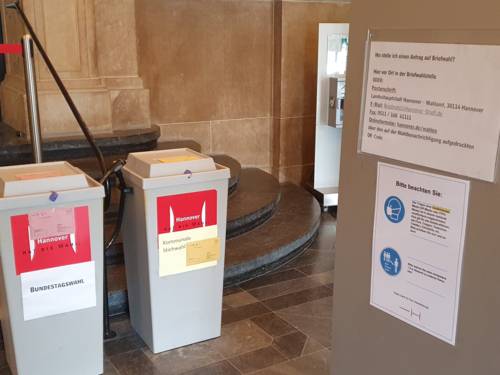 Ein Hinweisschild zu Briefwahlen und zwei Wahlurnen im Eingang des Neuen Rathauses