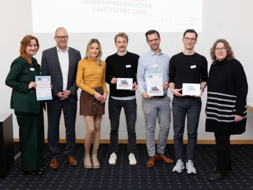 Sieben Personen, vier davon halten eine Auszeichnung in den Händen.