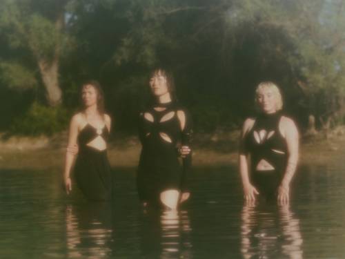 Drei Frauen in knappen Oberteilen stehen oberschenkeltief in einem See.