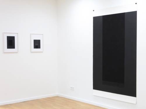 Zu sehen ist ein Galerieraum, an dessen Wände fast schwarze Bilder hängen.