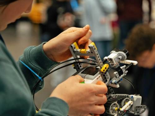 Kinderhände halten ein Robotermodell in den Händen.