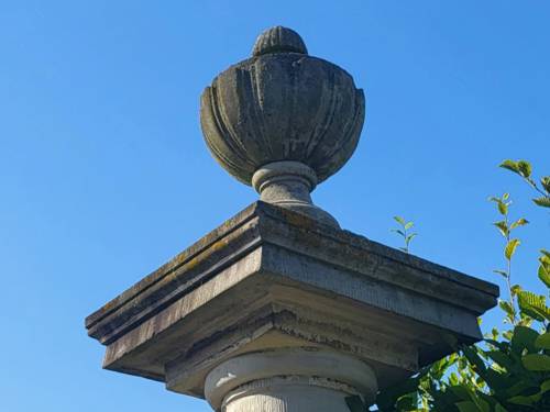 Eine alte Steinsäule mit einem Steinkelch oben vor blauem Himmel