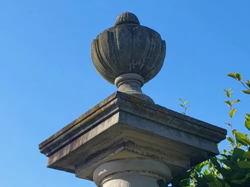 Eine alte Steinsäule mit einem Steinkelch oben vor blauem Himmel