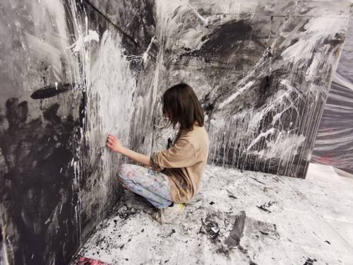 Eine junge Frau zeichnet mit Farbe ein Bild