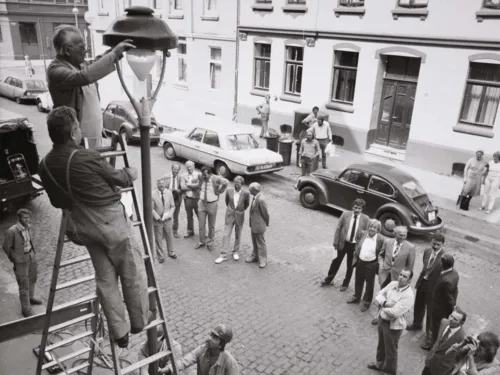 Arbeiter auf einer Leiter an einer Straßenlaternen. Historische Schwarz-Weiß-Aufnahme