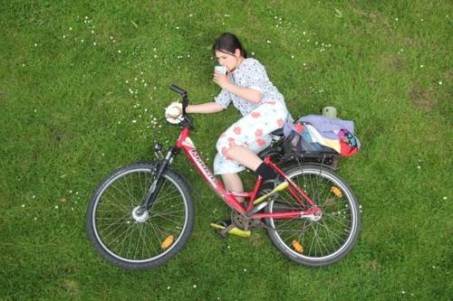 Mädchen liegt auf einer Wiese mit ihrem Fahrrad