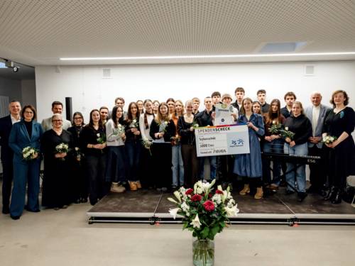 Eine große Gruppe hat sich für eine Scheckübergabe aufgestellt.