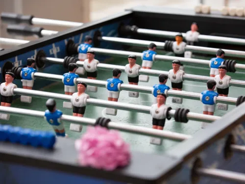 Krökeltisch / Kicker / Tischfußball mit Spielfiguren in den Trikotfarben Blau und Weiß.