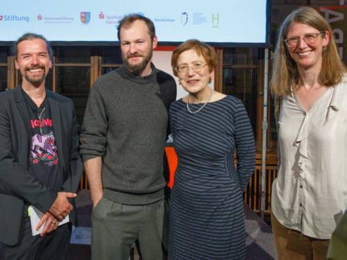 Vier Personen stehen nebeneinander und schauen in die Kamera.