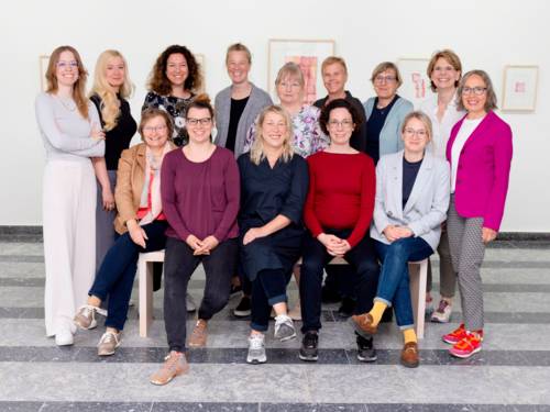 Eine Menschengruppe  aus vierzehn Personen, neun stehen, fünf sitzen.