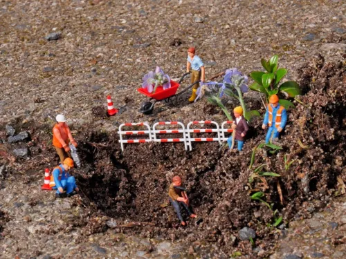 Mit Spielzeugfiguren und Blumen sowie Gräsernnachgebildete Baustelle