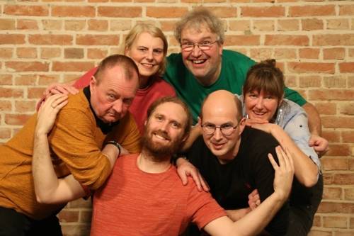 Menschen im Kreis vor einer Backsteinwand