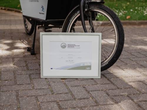 Gerahmte Auszeichnung vor einem Lastenfahrrad