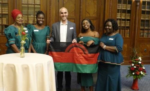 Eine Gruppe Personen in einem Raum zeigt eine Fahne von Malawi