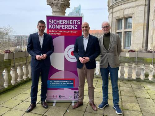 Drei Männer neben einem Aufsteller-ScHild zum Deutschen Präventionstag.