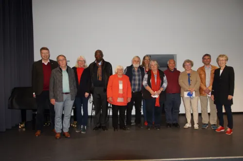 Männer und Frauen stehen auf einer Bühne. Es handelt sich um die gewählten Delegierten des Seniorenbeirates.
