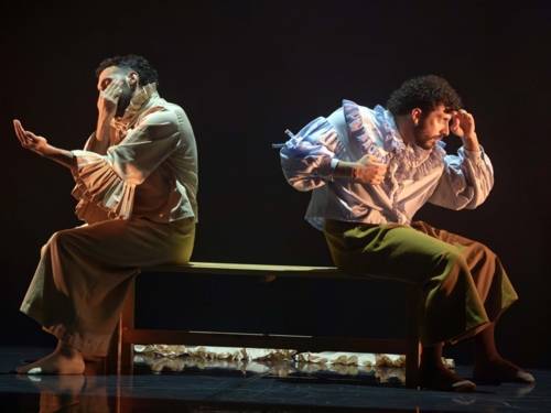 Zwei Tänzer sitzen mit dem Rücken zueinander auf einem Sofa.