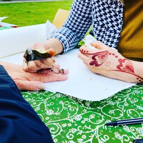 Eine Hand wird von einer anderen mit vielfältigen Henna-Muster bemalt.