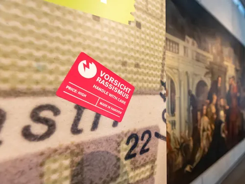 Blick in die Sonderausstellung "Von goldenen Kutschen und kolonialer Vergangenheit: Hannover, England und die Sklaverei", vom 12. Juli bis 13. November 2022 im HMH, hier der rechteckige rote Sticker "Vorsicht Rassismus"