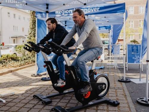 Zwei Männer sitzen auf Spinning-Bikes und treten in die Pedalen.