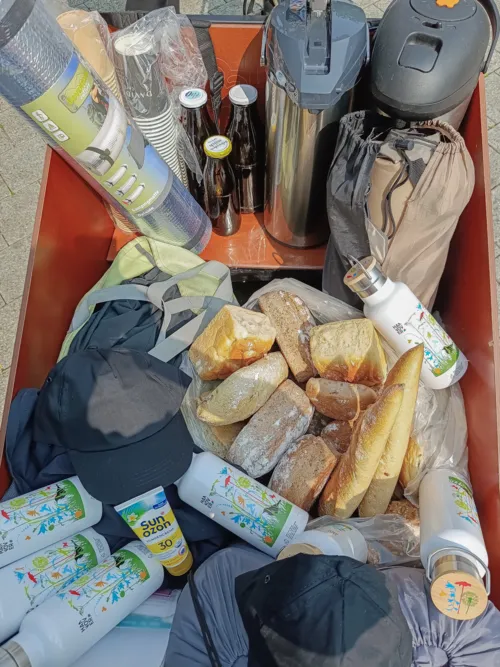 Sicht auf einen Transportbeh&auml;lter mit Br&ouml;tchen, Thermoskannen, Bechern, Edelstahl-Trinkwasserflaschen und Sonnencreme