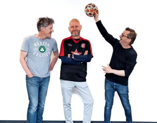 Drei Männer, einer hält einen Ball in die Höhe.