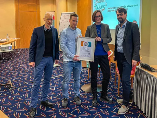 Vier Personen bei der Übergabe einer Auszeichnung in einem Konferenzraum.