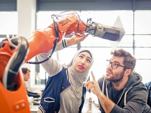 Eine Frau und ein Mann mit einem Industrieroboter.