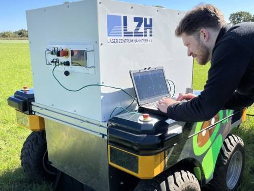 Mann an einem Laptop auf einem kleinen Wagen mit der Aufschrift "LZH Laserzentrum Hannover".
