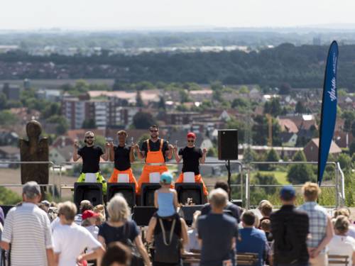 Vier performende Personen auf einem Berg vor Publikum