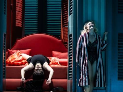 Blick durch eine Tür auf eine Person, die auf einem Bett liegt. Neben der Tür steht eine Frau in Bademantel.