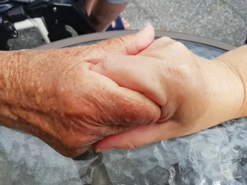 Die Hände einer jüngeren Person, die die Hände einer älteren Person halten
