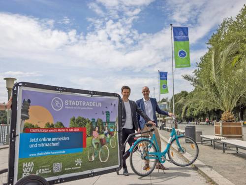 Zwei Herren mit einem Fahrrad und einem Werbebanner fürs Stadtradeln 2024.