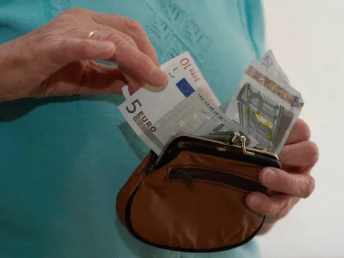 Hände halten eine Geldbörse und sortieren Geldscheine.