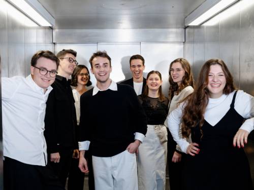 Die jeweils vier jungen Sängerinnen und Sänger des Ensembles stehen in einem Fahrstuhl.
