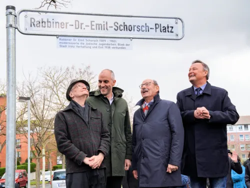 Fünf Personen bei der Enthüllung eines Straßenschildes.