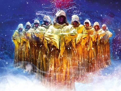 Zu sehen sind die Mitglieder der Gruppe Gregorian. Die tragen goldene Roben vor einem weihnachtlich gestimmten Hintergrund.
