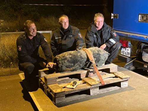 Drei Mitarbeiter des Kampfmittelbeseitigungsdienstes mit einer entschärften Fliegerbombe in Brink-Hafen.