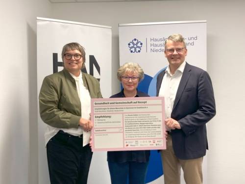 Zwei Frauen und ein Mann halten gemeinsam ein überdimensionales Rezept in den Händen.