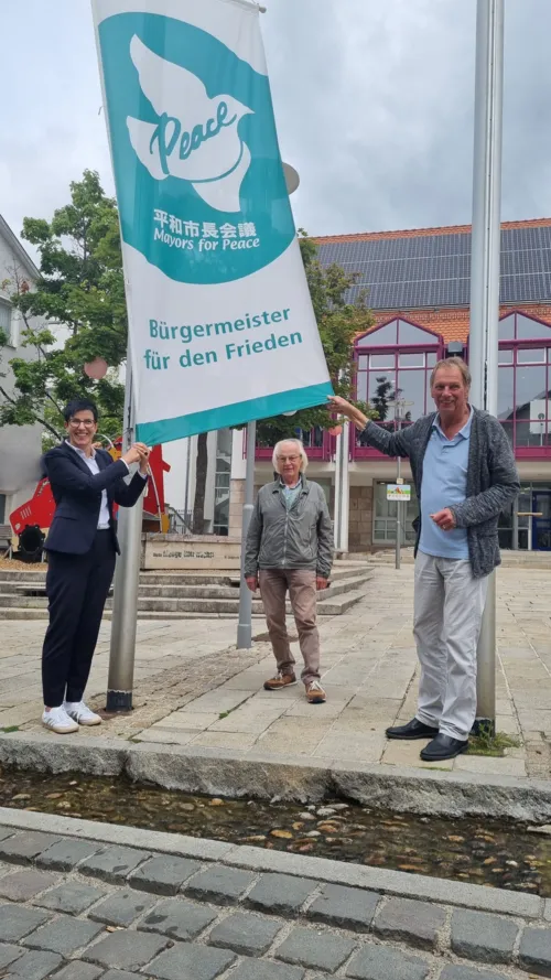 Carmen Haberstroh, Oberbürgermeisterin von Metzingen, Reinhard Glatzel und Werner Schulz vom ökumenischen Arbeitskreis Frieden (vlnr) beim Hissen der Mayors for Peace Flagge