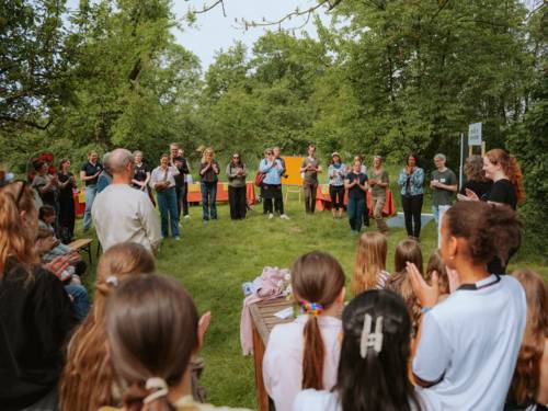 Menschen auf einer Wiese. Sie lauschen einer musikalischen Darbietung.