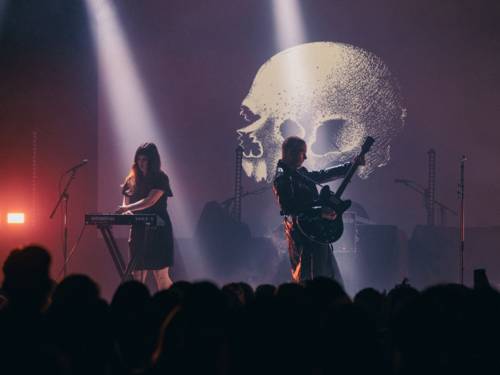 Eine Frau spielt auf einer Bühne auf einem Symptheziser, neben ihr spiel ein Mann E-Gitarre.