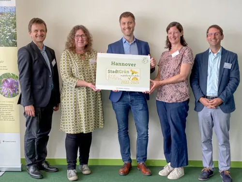 F&uuml;nf Personen mit einem Schild.
