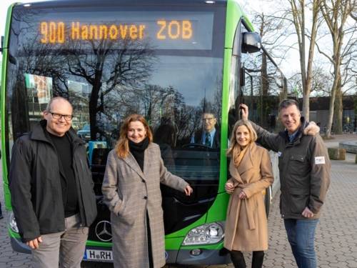 Zwei Frauen und zwei Männer stehen vor einem Bus der Linie 900