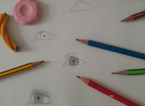 Ein schritt für schritt gezeichnetes Auge mit Stiften und anderen Zeichen Utensilien drum rum.