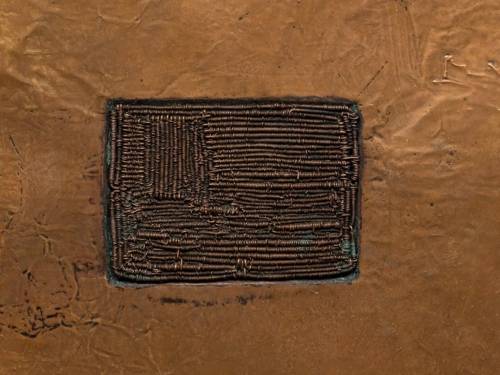 Zu sehen ist eine Fotografie eines Rechteckes aus metallenen Federn, das in eine Kupferplatte eingesetzt ist.